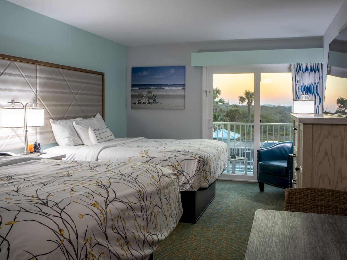 A cozy hotel room with two beds, stylish bedding, a balcony with a scenic view, and a beach-themed wall art.