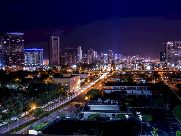 A cityscape at night with illuminated buildings and streets, showcasing a vibrant urban environment under a dark sky.